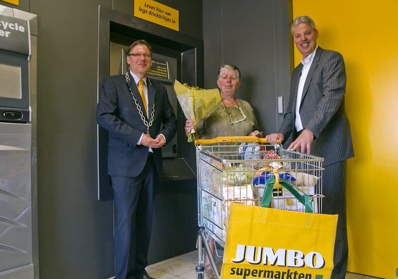 Felicitaties van burgemeester Niels Joosten (links) en supermarktondernemer Casper Heine (rechts) aan de klant met het jubileum-blikje. 